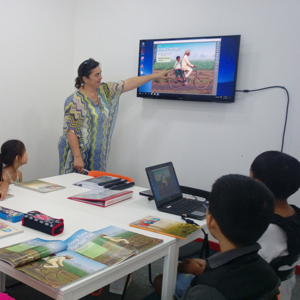Teacher teaching students with video on TV in class