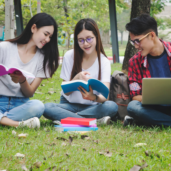 College students studying with books and laptop outdoors