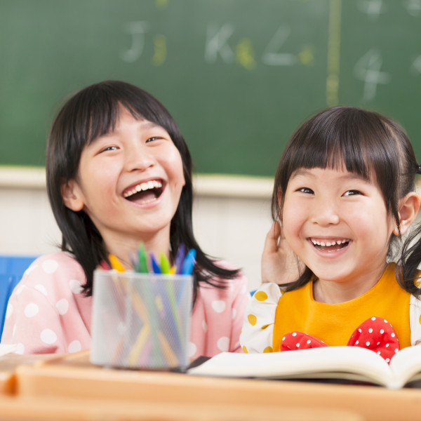 Two primary school girls laughing in class